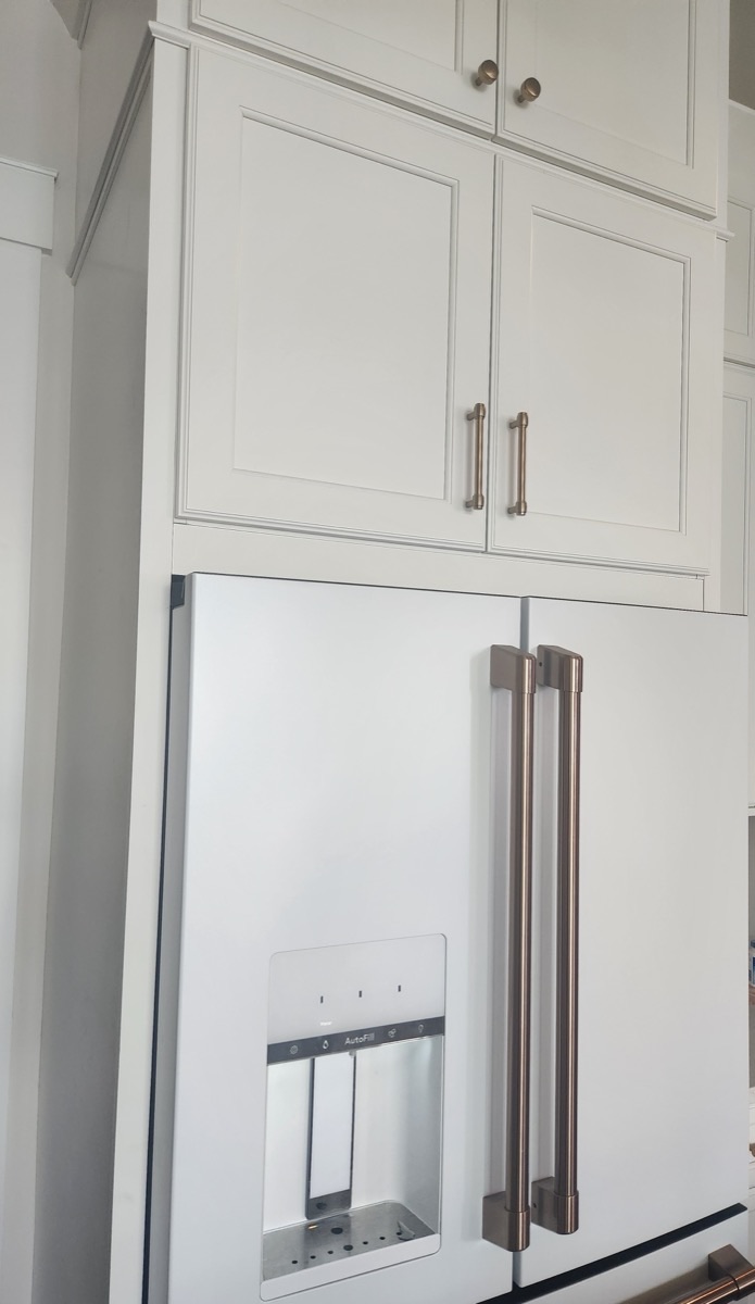 Kary's white GE Caf&eacute; refrigerator with brushed hardware, built in below matching cabinetry